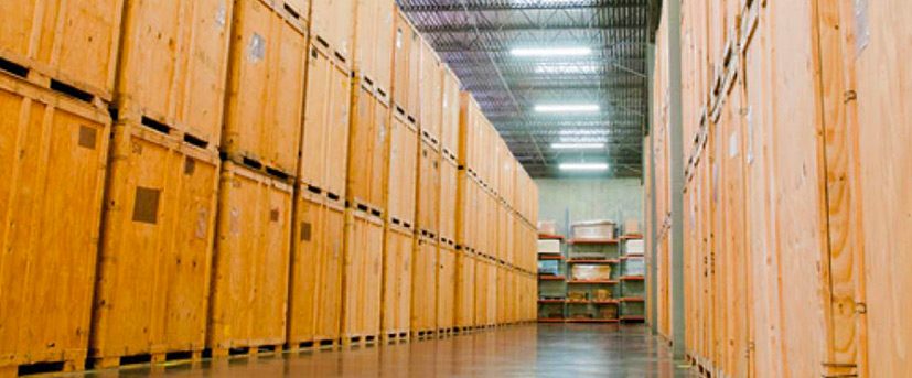The inside of a storage warehouse is shown, with two rows of palletized wooden crates stacked three-high.